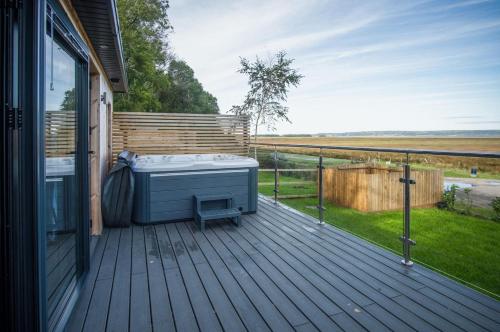 a deck with a hot tub on the side of a house at The Rhossili Bay Secret - 1 Bed Cabin - Landimore in Gowerton