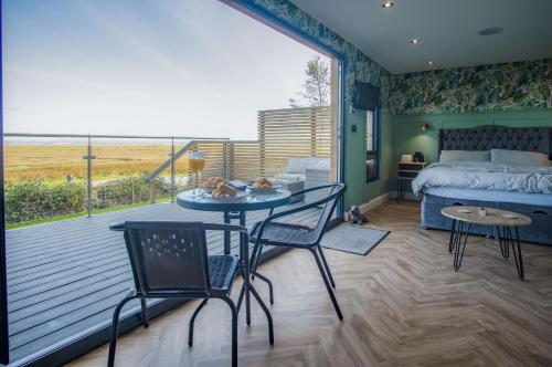 a bedroom with a bed and a table and chairs at The Rhossili Bay Secret - 1 Bed Cabin - Landimore in Gowerton