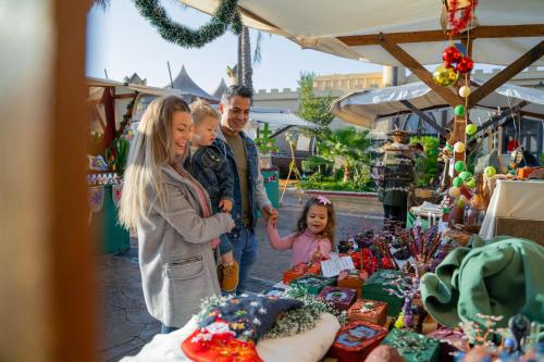 a family standing in front of a market with christmas merchandise at Magic Robin Hood in Albir