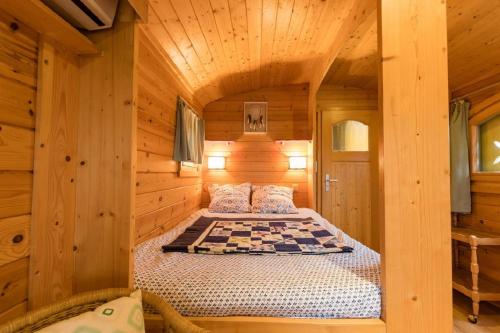 - une chambre avec un lit dans une cabane en bois dans l'établissement Roulotte de la Villa Font Vive - Tout équipée, tout confort, situation idéale Sud Ardèche, à Grospierres