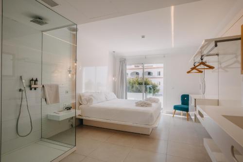 um quarto branco com uma cama e uma cabina de duche em vidro em Lago Resort Menorca - Casas del Lago Adults Only em Cala'n Bosch