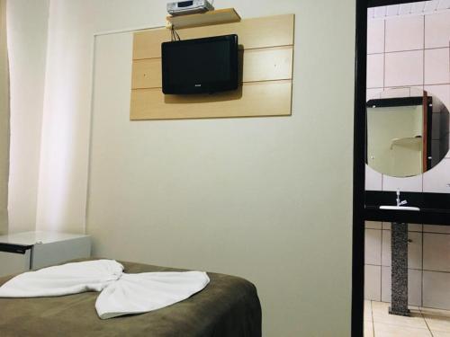 um quarto com uma cama e uma televisão na parede em Hotel Paris em Curitibanos