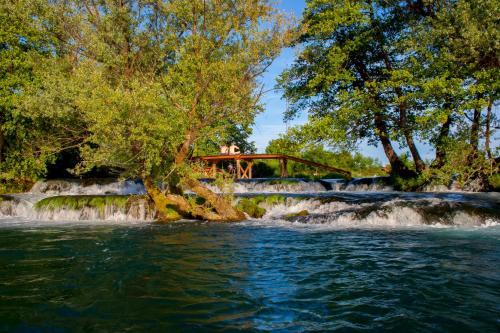 eine Brücke über einen Fluss mit einem Wasserfall in der Unterkunft Holiday Homes Pozitiva in Bihać