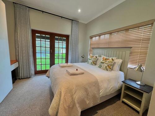 a bedroom with a large white bed with a window at Le Rendezvous in Dullstroom