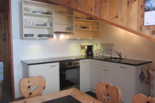 La cuisine est équipée de placards blancs et d'un four avec plaques de cuisson. dans l'établissement Vichava 8, Süd, à Ftan
