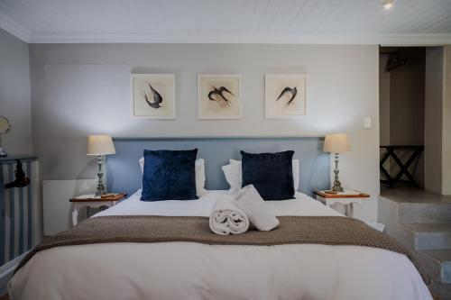 a bedroom with a large white bed with blue pillows at A Hilltop Country Retreat in Swellendam