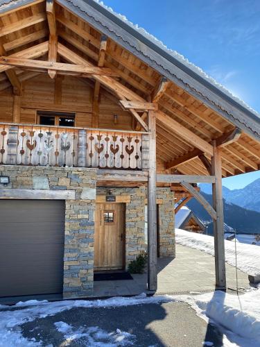 a wooden building with a garage in the snow at Chalet Fontaines in LʼHuez