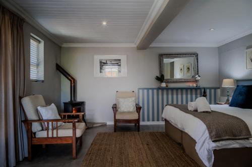 a bedroom with a bed and a chair and a mirror at A Hilltop Country Retreat in Swellendam