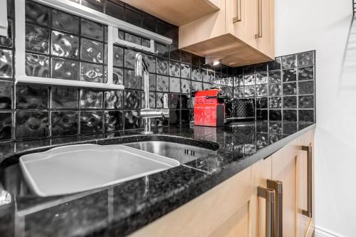 a kitchen with a sink and a black tiled wall at Beautiful 2 bed apartment in the heart of the city in Norwich