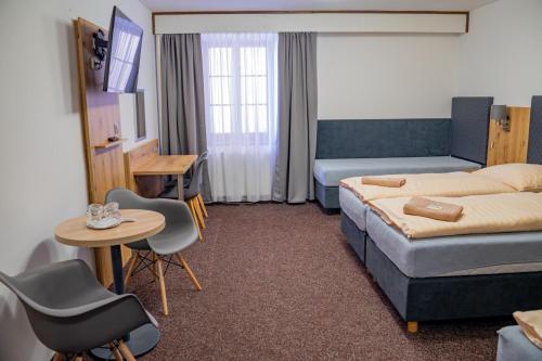 Hotel Zlatá Labuť في كراليكي: غرفة فندقية بسرير وطاولة وكراسي