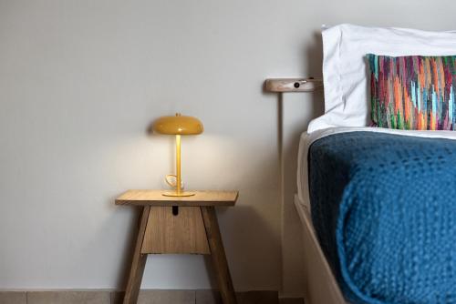 a bed and a table with a lamp on it at Athermi Suites - Adults Only in Megalokhori