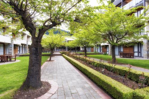 a walkway in front of a building with trees at Novotel Queenstown Lakeside in Queenstown