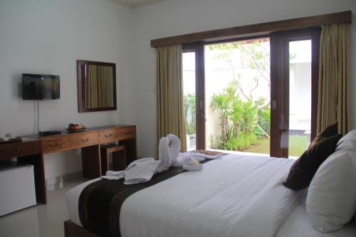 a bedroom with a large white bed with a window at Anggie Stay in Kerobokan
