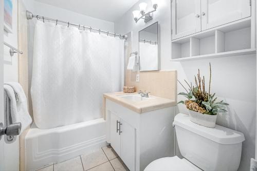 a white bathroom with a toilet and a sink at San Clemente Shores in San Clemente