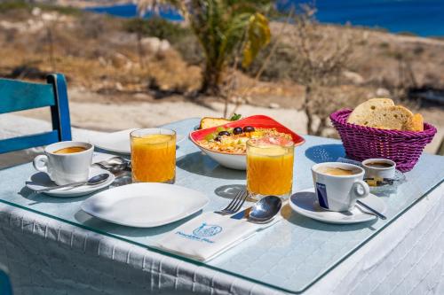 Poseidon Blue Gastronomy Hotel في Afiartis: طاولة مع طعام ومشروبات وصحن من الخبز