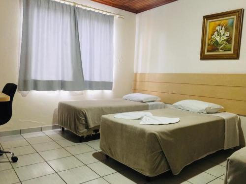 Duas camas num quarto com uma janela em Hotel Paris em Curitibanos