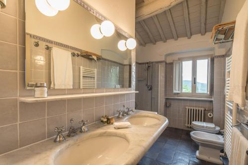 a bathroom with two sinks and a toilet and a mirror at Casolese di Vignamaggio in Greve in Chianti