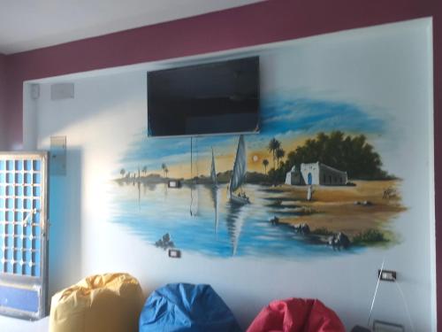 a painting on a wall with a tv on it at Nukud guest house in Aswan