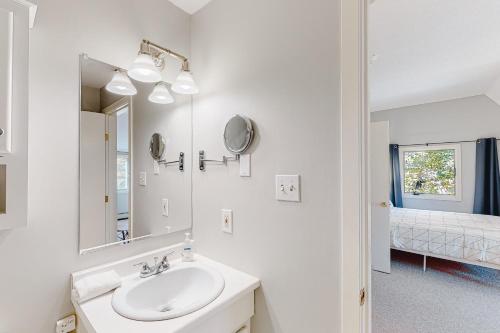 Baño blanco con lavabo y espejo en Kingswood Mountainside Retreat, en White River Junction