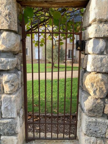an iron gate in a stone wall with a yard at Château de Mazières in Tendu