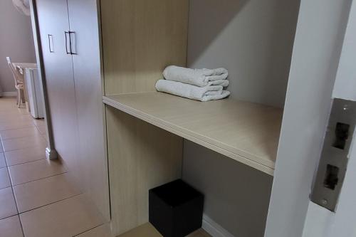 een badkamer met handdoeken op een plank bij SHALIMAR GARDENS HOTEL in Kaapstad
