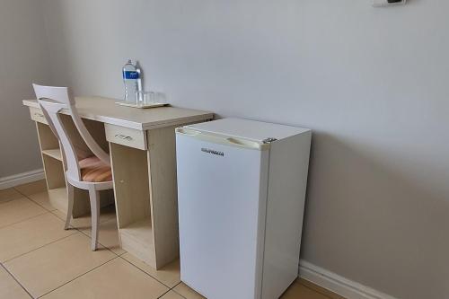 a white refrigerator in a kitchen with a table at SHALIMAR GARDENS HOTEL in Cape Town