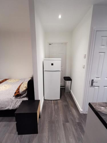 a white room with a bed and a white refrigerator at Studio self contained double bedroom in London