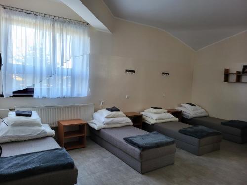 a room with three beds and a couch and a window at Hotelik OSiR Lubawa in Lubawa