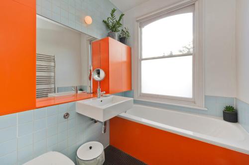 baño de color naranja con lavabo y aseo en Veeve - The Artist's House en Londres