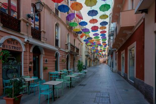 an alley with tables and umbrellas hanging from ceilings at La Scala del Sale in Iglesias