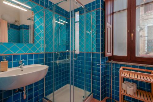 a blue tiled bathroom with a sink and a shower at La Scala del Sale in Iglesias