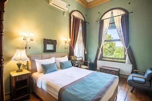a bedroom with a bed and a chair and a window at Büyükada Anastasia Meziki History Mansion in Buyukada