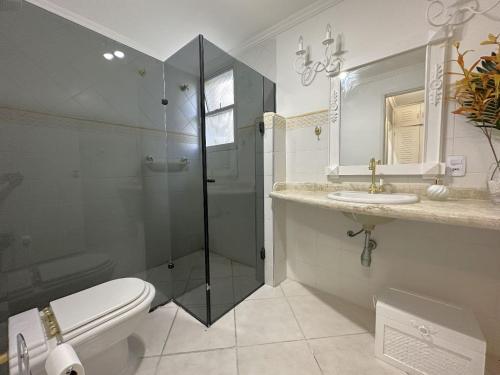uma casa de banho com um chuveiro, um WC e um lavatório. em Pé na Areia a Poucos Metros -Apartamento Guarujá Pitangueiras no Guarujá
