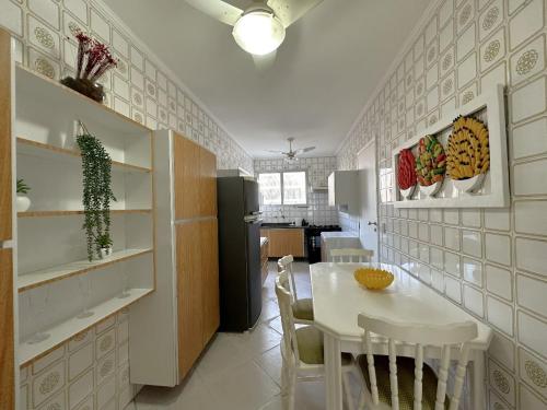 a kitchen and dining room with a table and a refrigerator at Pé na Areia a Poucos Metros -Apartamento Guarujá Pitangueiras in Guarujá
