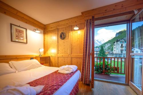 ein Schlafzimmer mit einem Bett und einem großen Fenster in der Unterkunft Hotel Lo Scoiattolo in Gressoney-la-Trinité