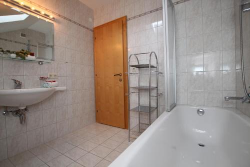 a bathroom with a tub and a sink and a mirror at Bella Vista Apartments in Nauders