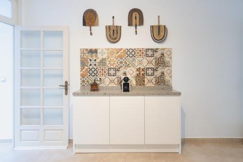 a kitchen with white cabinets and a tile wall at Casa Blanca in Estepona