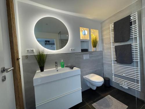 ein Badezimmer mit einem Waschbecken, einem WC und einem Spiegel in der Unterkunft Gleis 12 , kontaktloser 24-7-Check In, barrierefrei ,Smart TV, W-LAN, Parkplatz kostenlos in Bückeburg