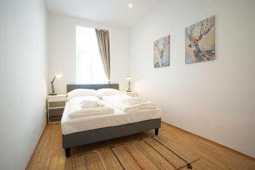 1 dormitorio con 1 cama con sábanas blancas y ventana en Chic Newly-Renovated Apartment Steps from Subway in Vienna's Hernals District, en Viena