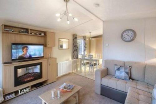 a living room with a couch and a tv at 3 Bedrooms Loch Views Heated Pool Close To Beaches in Newton Stewart