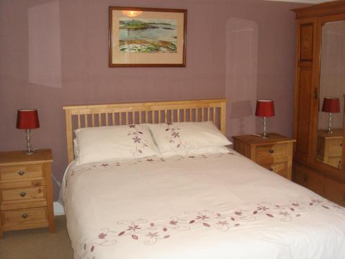 a bedroom with a white bed with flowers on it at Braeside cottage in Tarskavaig