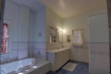 a large bathroom with a tub and a sink at Kitty's Beach House in Placencia