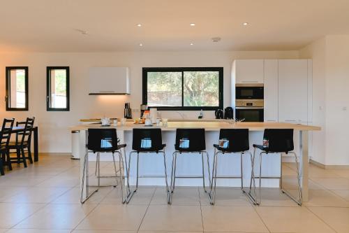 a kitchen with a large island with bar stools at Villa Terrasse et Piscine à l'entrée de Porticcio in Cauro