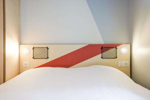a bedroom with a white bed and two lights at ibis Budget Villemomble in Villemomble