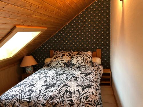 1 dormitorio con 1 cama con edredón blanco y negro en HERMINE en Morillon