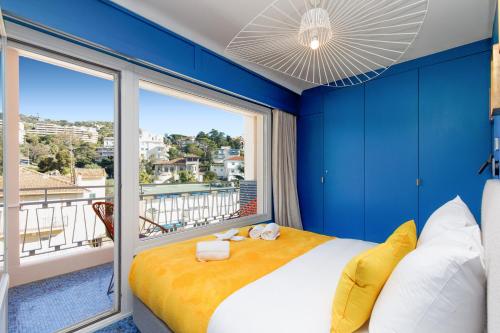 - une chambre bleue avec un lit et une grande fenêtre dans l'établissement Les Légendes YourHostHelper, à Cannes