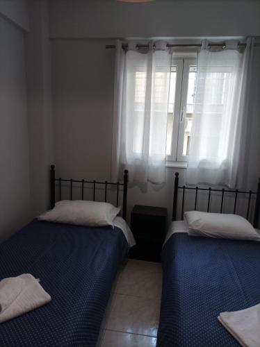 two beds in a room with a window at Eirini's Apartment in Missolonghi