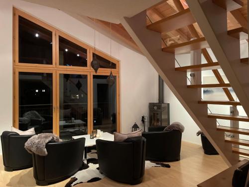 a living room with a table and chairs and stairs at Victoria's Home - luxurious penthouse in Saas-Fee