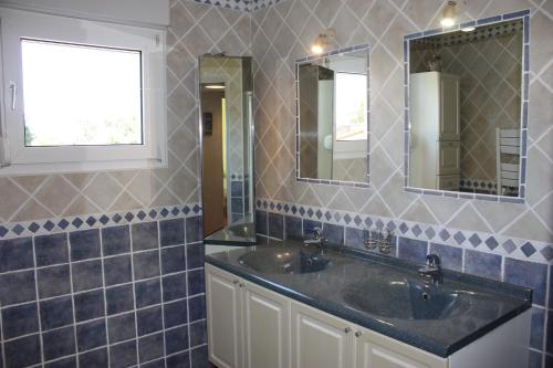a bathroom with two sinks and two mirrors at Les chambres d'hôtes d'Eloïse, piscine privée in Aramon