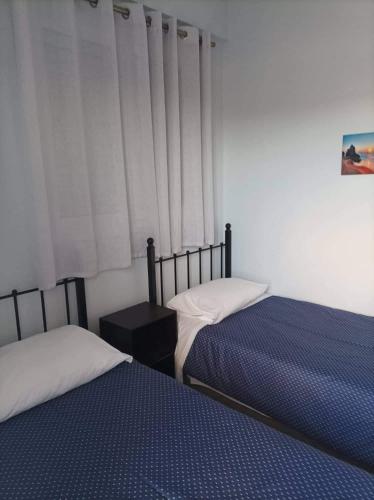 a bedroom with two beds and a window with curtains at Eirini's Apartment in Missolonghi